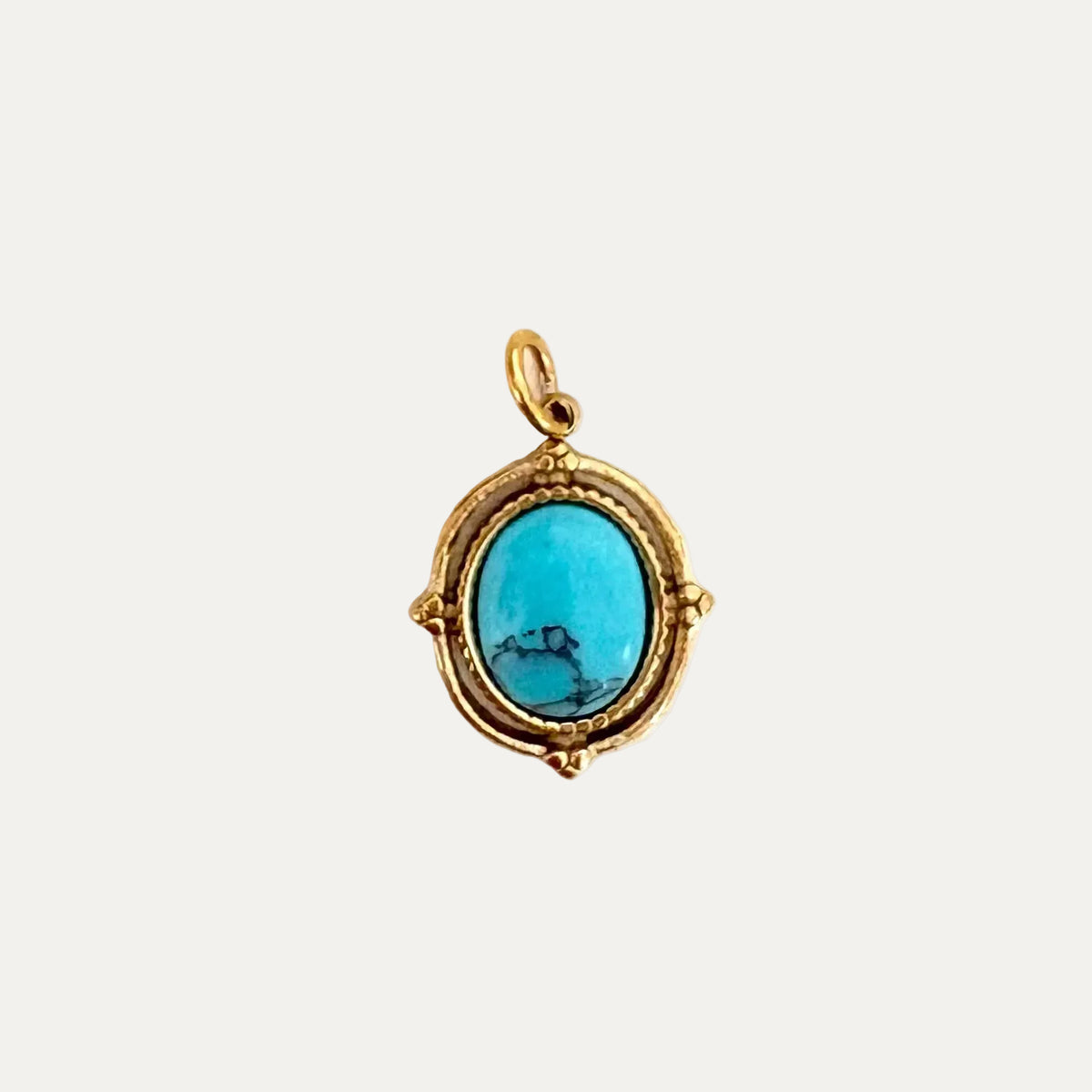 An oval turquoise gemstone pendant with a textured gold frame and bail, shown on a plain white background.