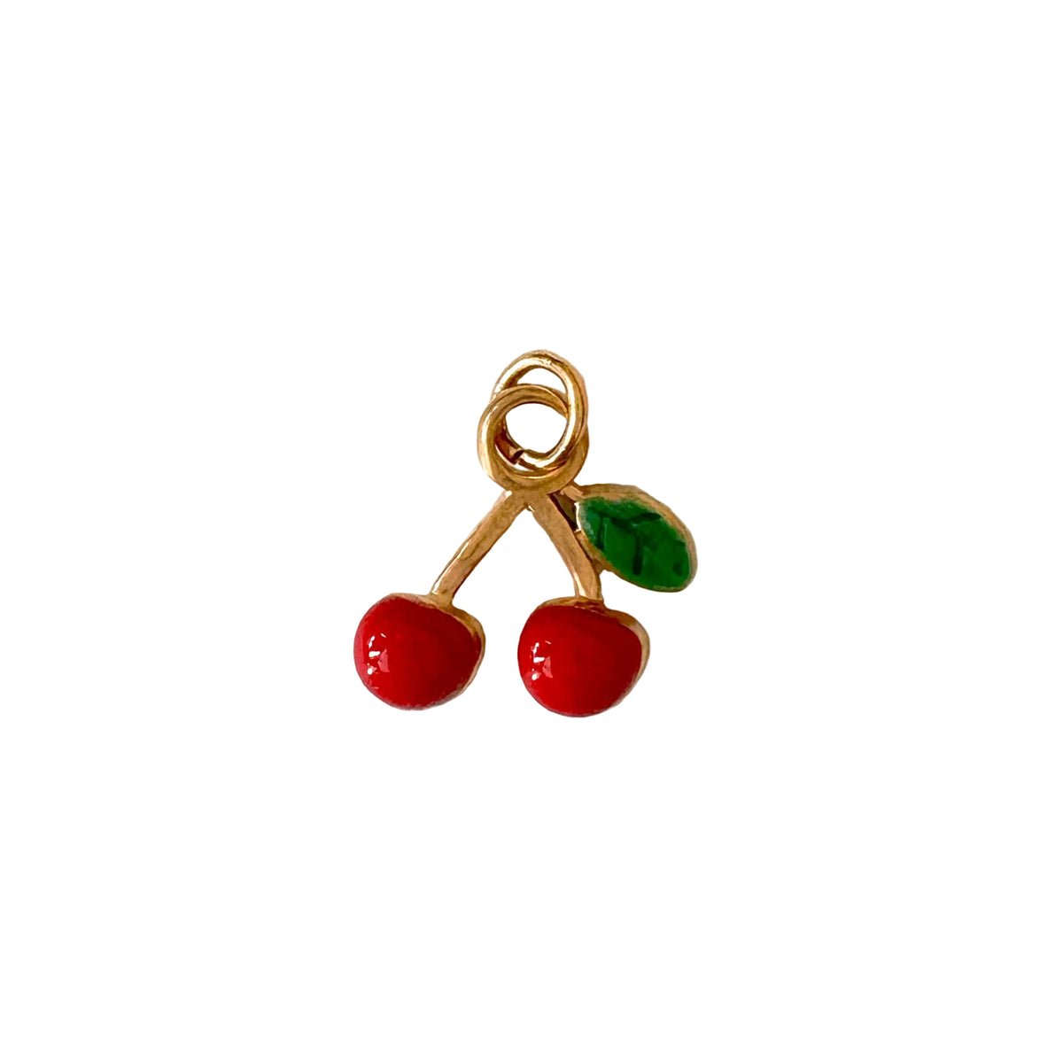 Gold charm with red berries and a green leaf on a white background