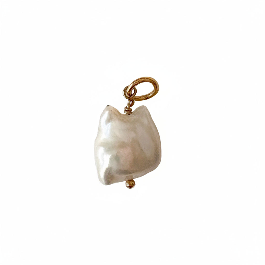 Pearl charm with gold clasp on a textured white background