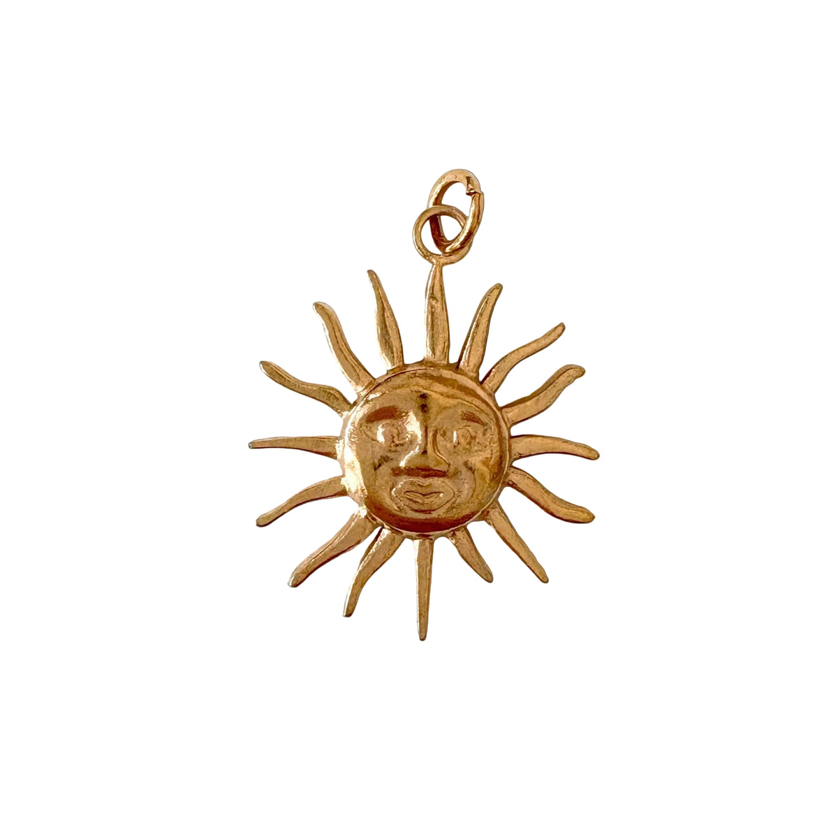 Gold sun-shaped pendant with face design on a white background