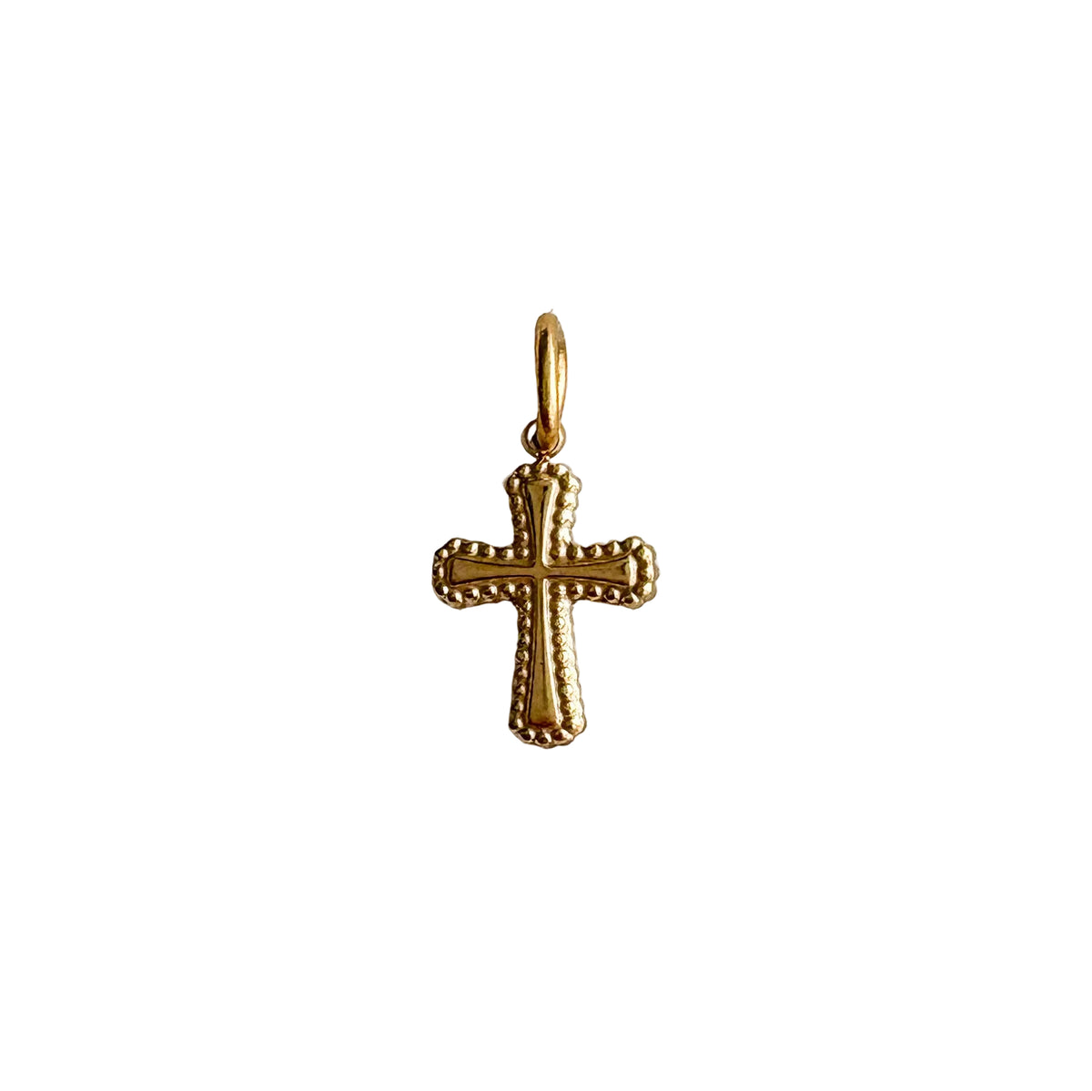 Gold cross pendant on a textured white background