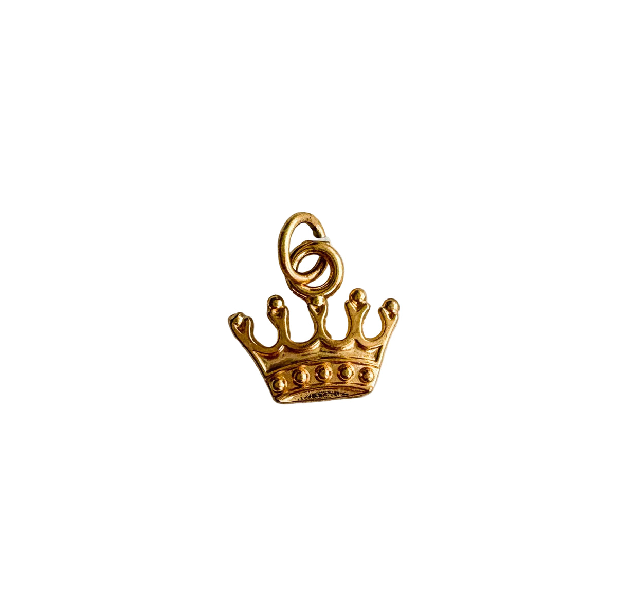 Gold crown charm on a textured white background