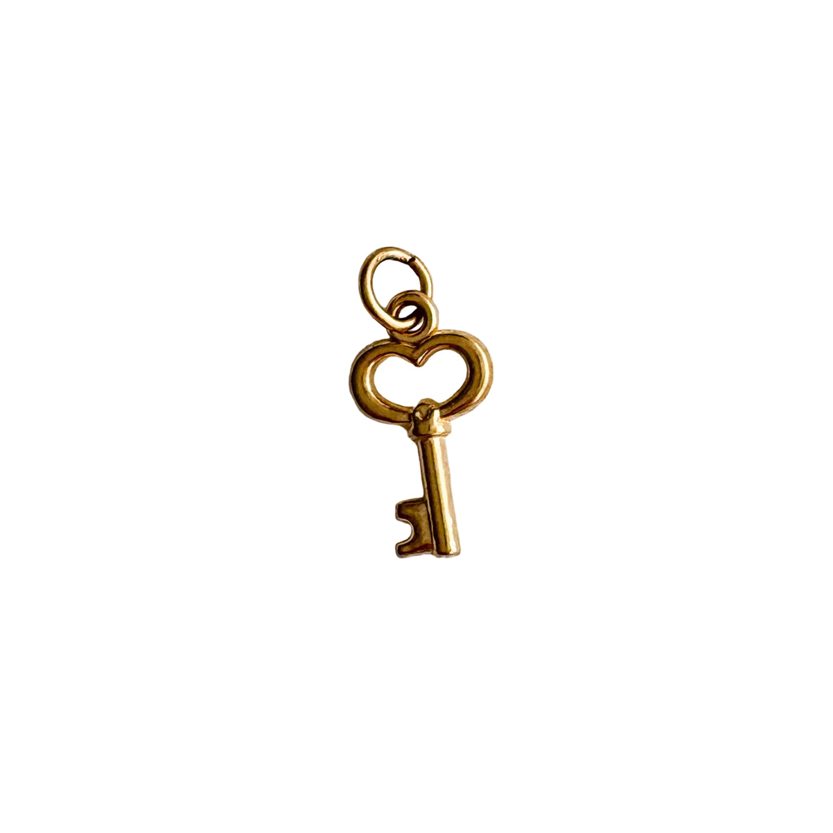 Gold key-shaped charm on a textured white background