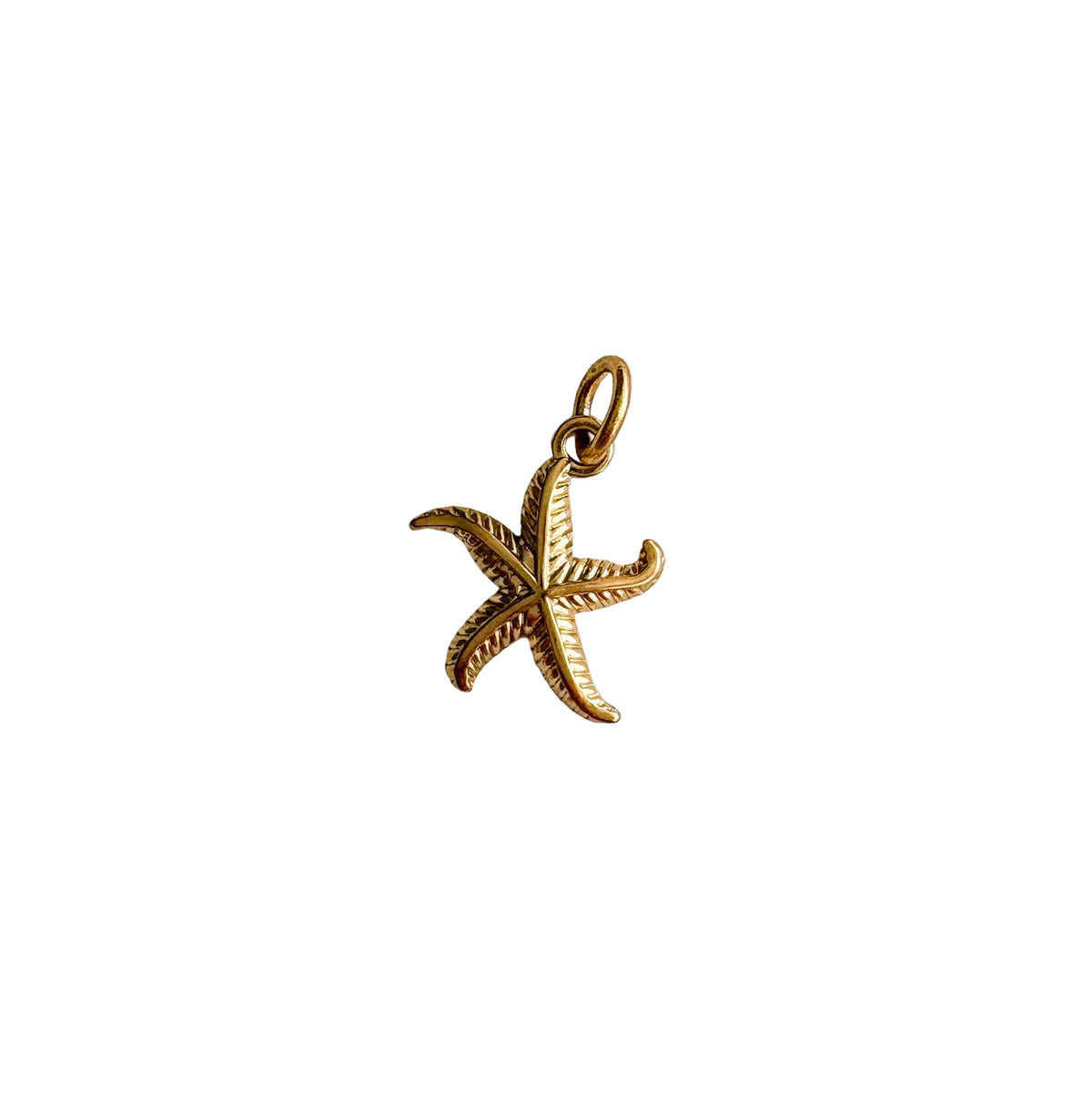 Gold starfish pendant on a white fabric background