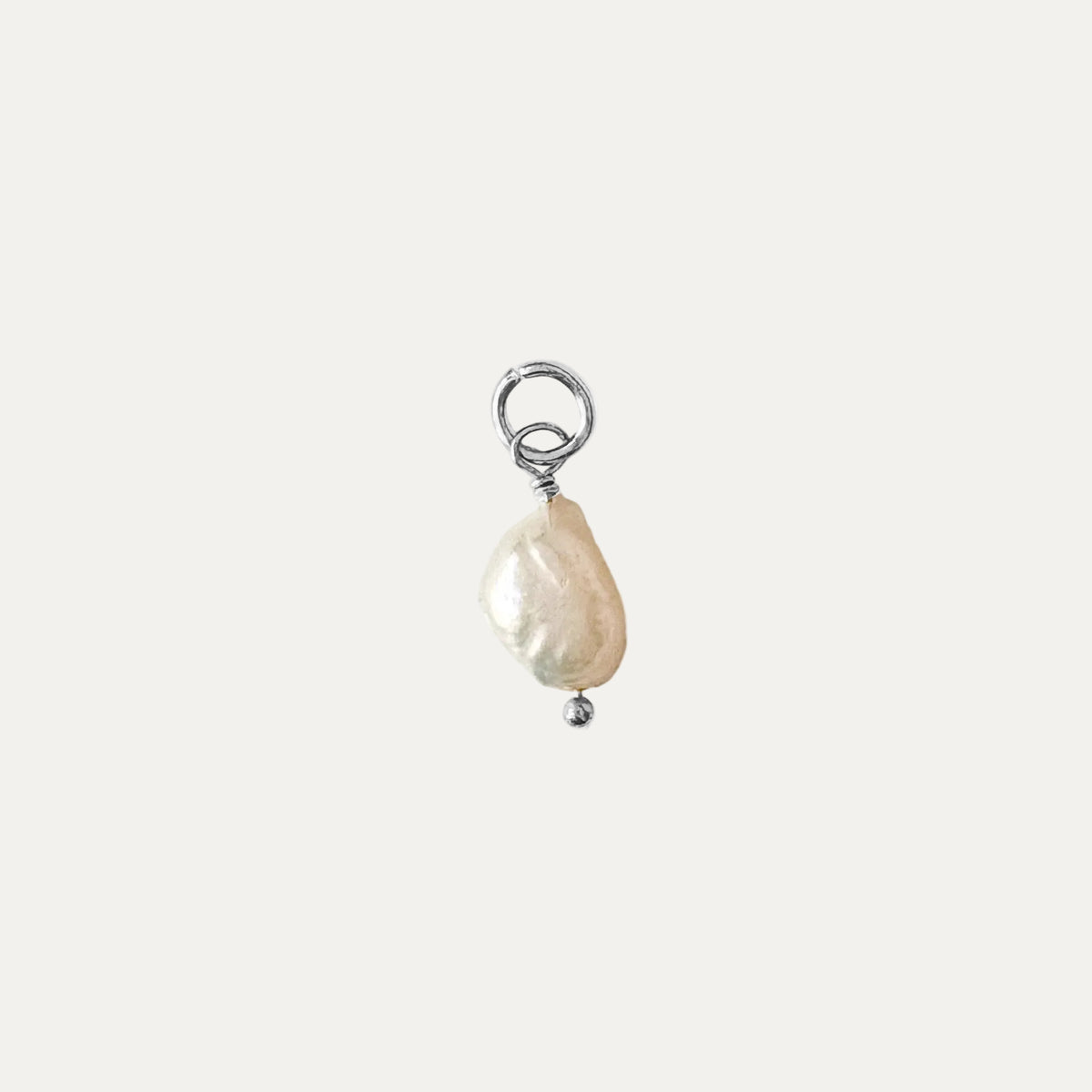 A single baroque pearl charm in silver wire wrapping with a small silver bead at the bottom and a jump ring at the top, shown on a plain white background.