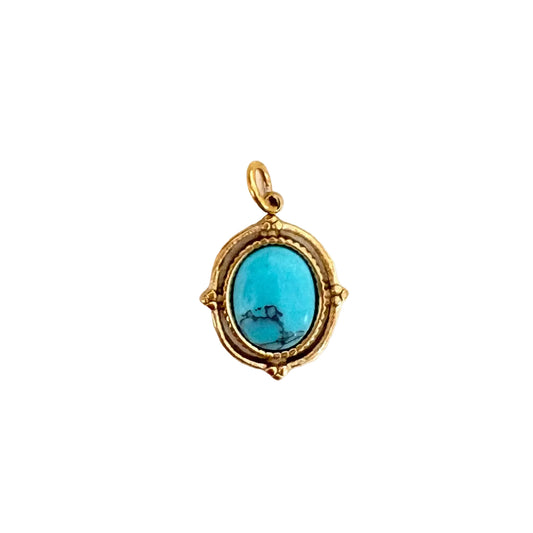 An oval turquoise gemstone pendant with a textured gold frame and bail, shown on a plain white background.