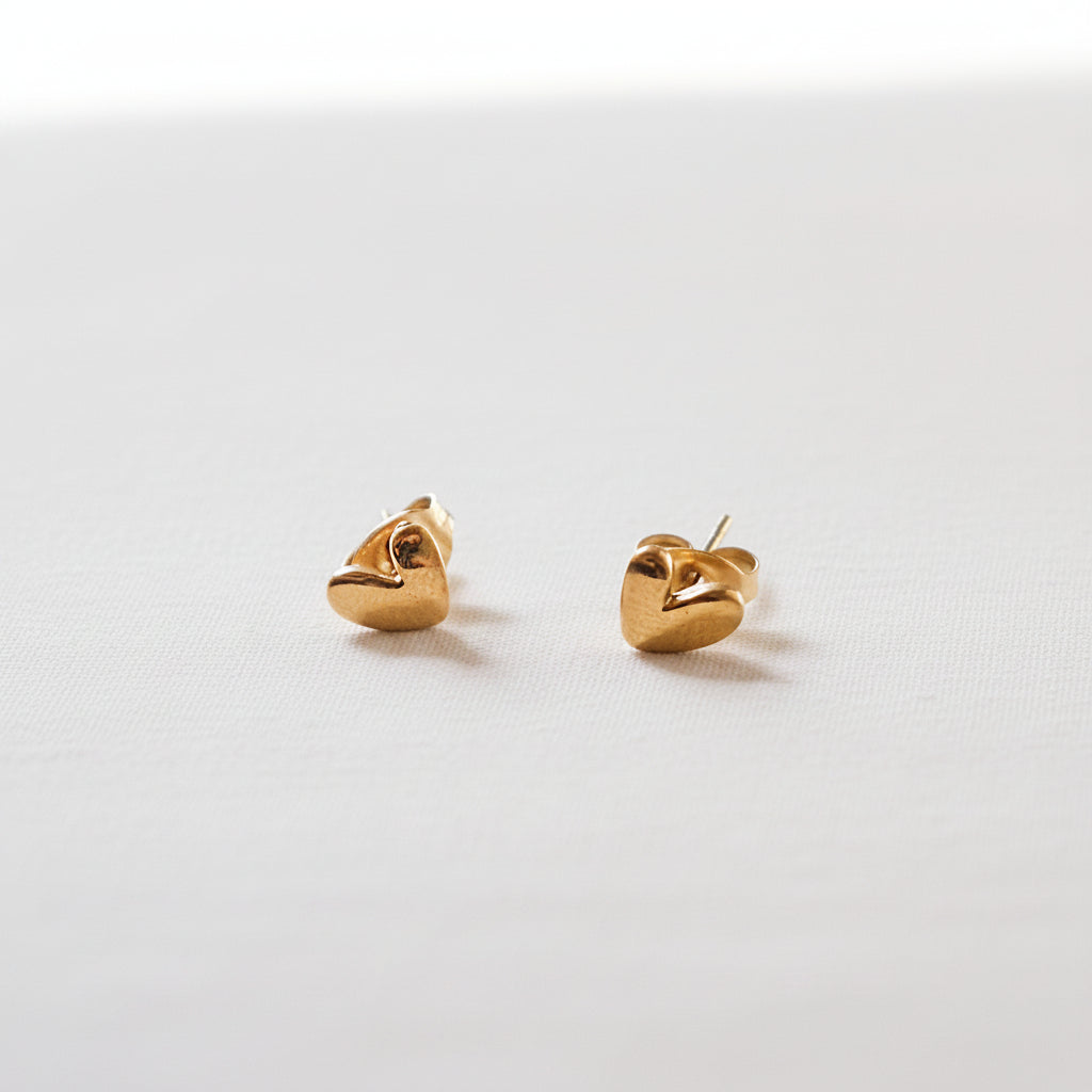 Pair of gold heart-shaped earrings on a white background