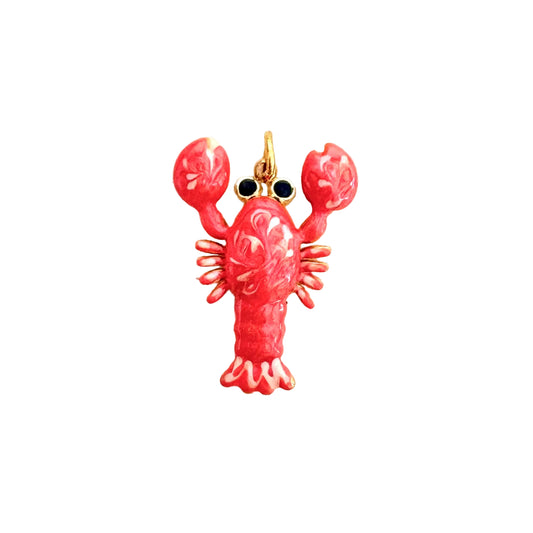 A lobster-shaped charm or pendant with a glossy pink-red enamel body, gold-tone metal outlines, and small black eye details, centered on a plain off-white background.
