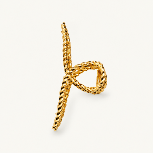 A gold-toned twisted rope ring with a knotted design, photographed on a clean off-white background.